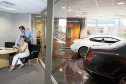 Woman and salesman sitting in car showroom office